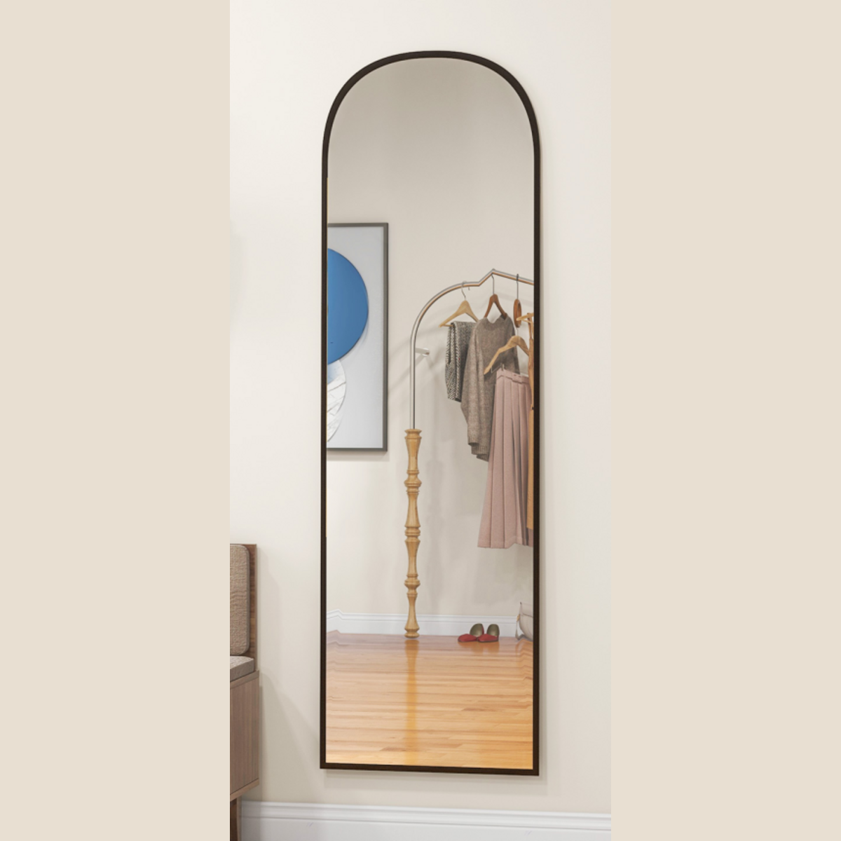 Arched black full-length mirror mounted vertically on a wall