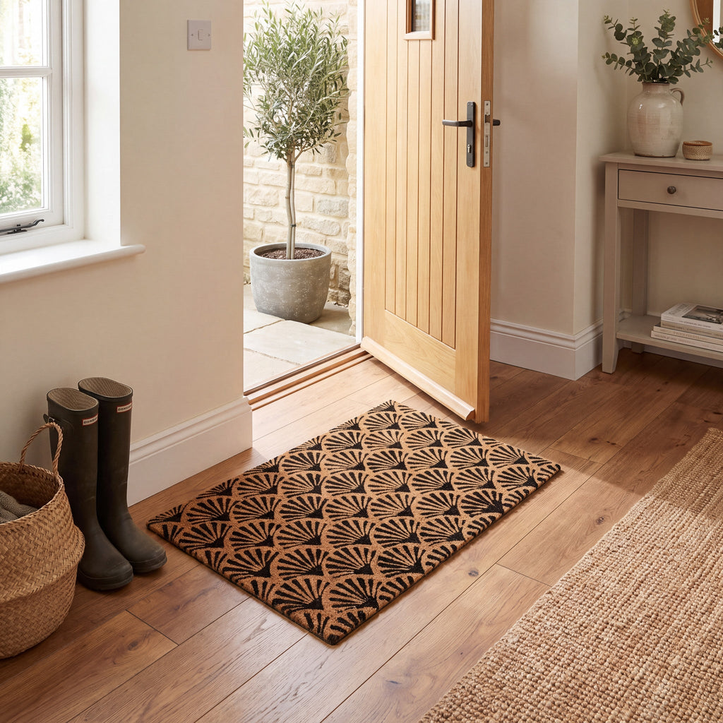 Black scallop pattern coir doormat beside an open wooden front door