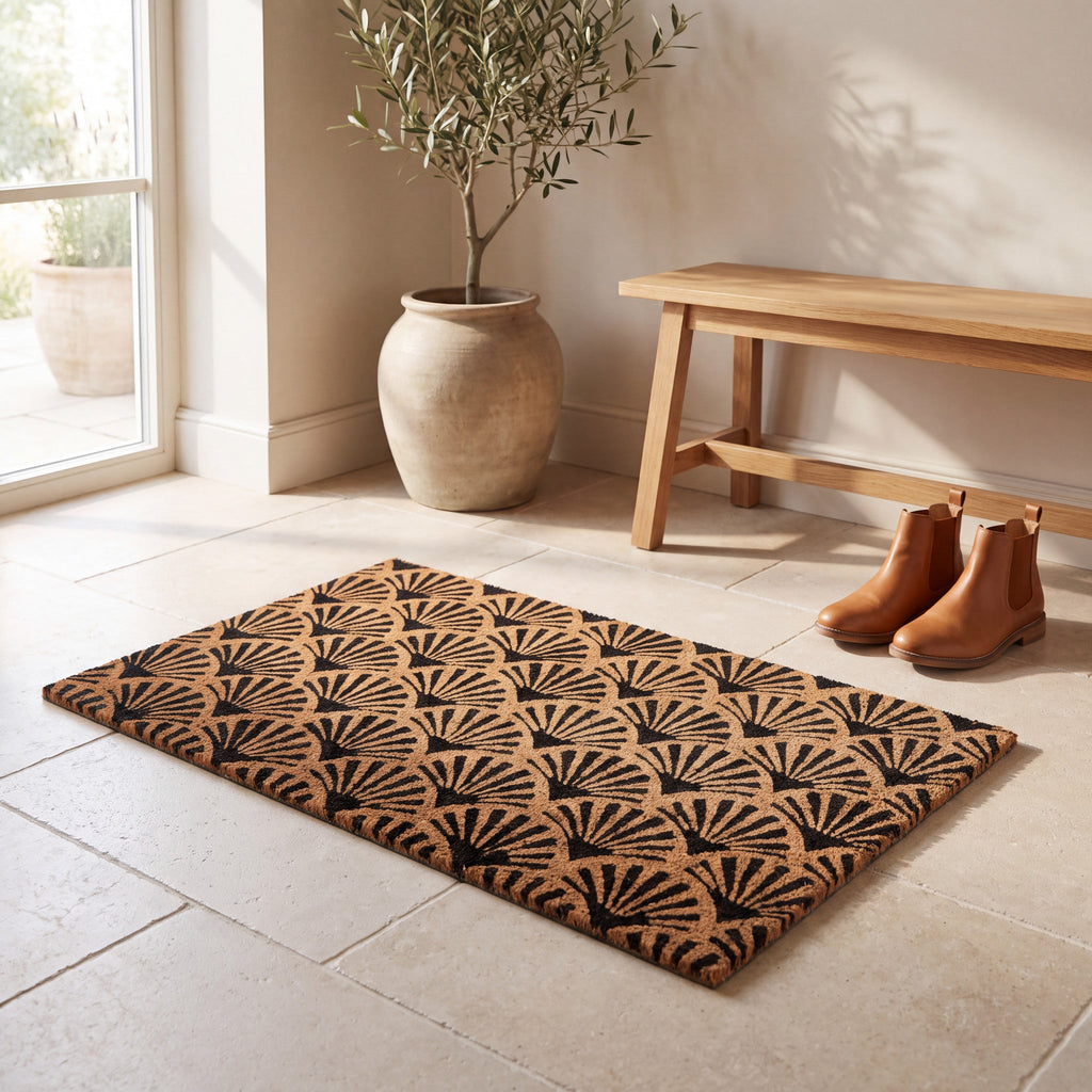 Coir doormat with black scallop pattern styled on a light stone hallway floor