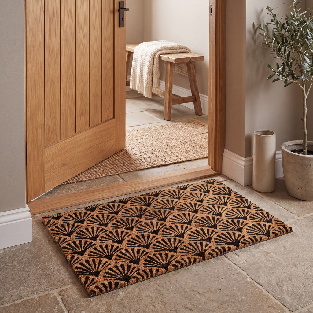 Coir entrance mat with black scallop pattern in a warm natural hallway