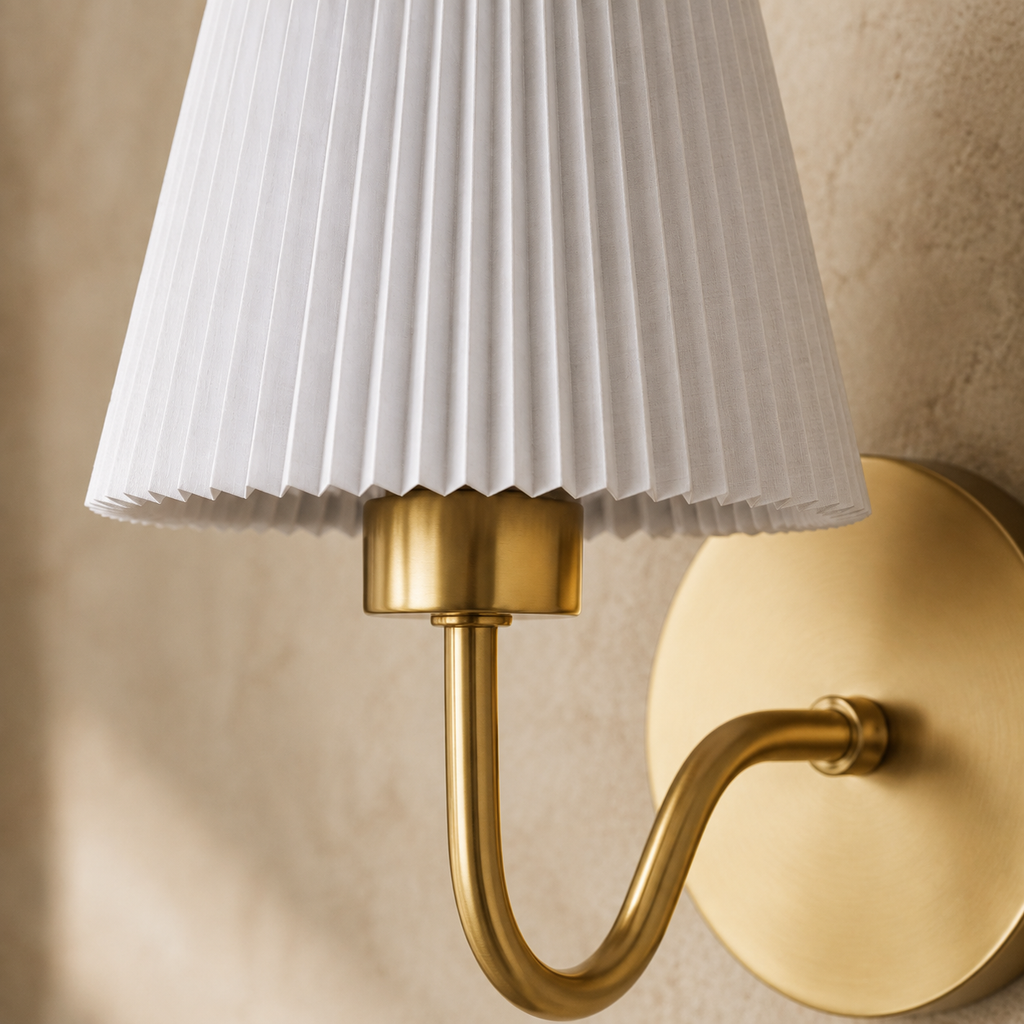 Close detail of pleated white shade and brushed gold curved wall light