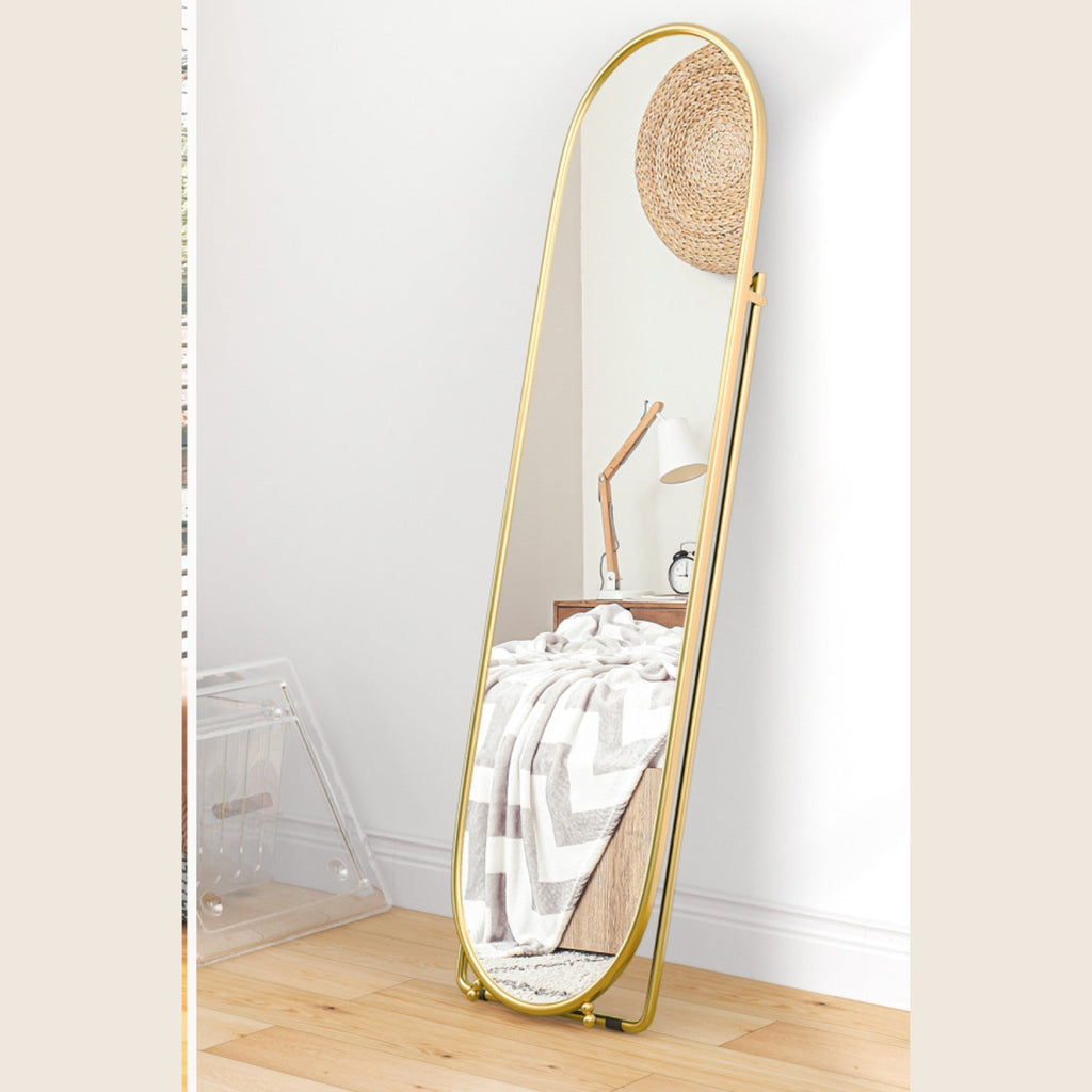 Gold oval full-length mirror leaning securely against a wall
