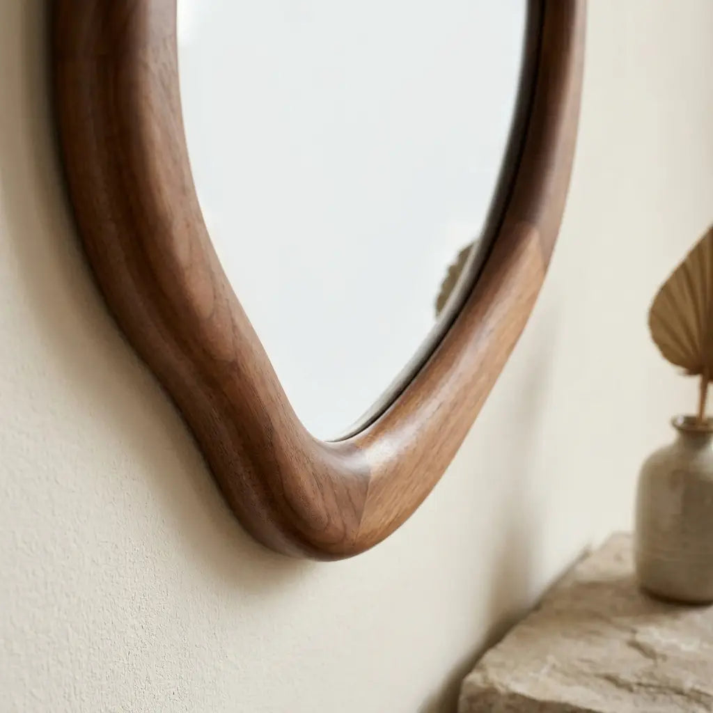 Irregular walnut wall mirror measuring 50 by 70cm in soft natural daylight in a hallway