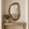 Irregular walnut wall mirror measuring 50 by 70cm shown at room scale in a hallway