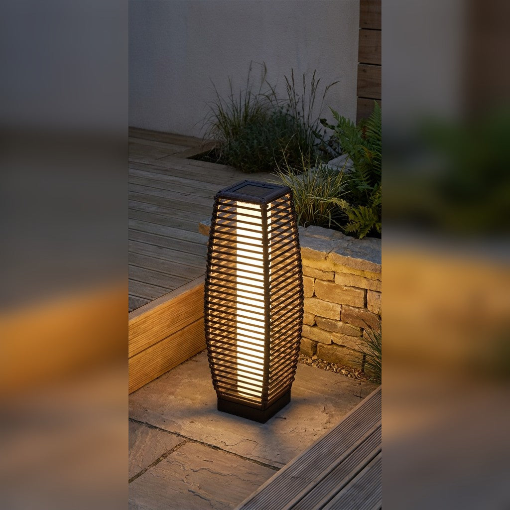 Outdoor solar floor lamp with warm white light beside a garden path