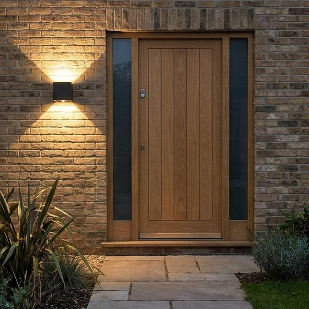Outdoor wall light with sensor illuminating a front door and stone wall