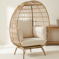 Natural rattan egg chair with cream cushions on a white background