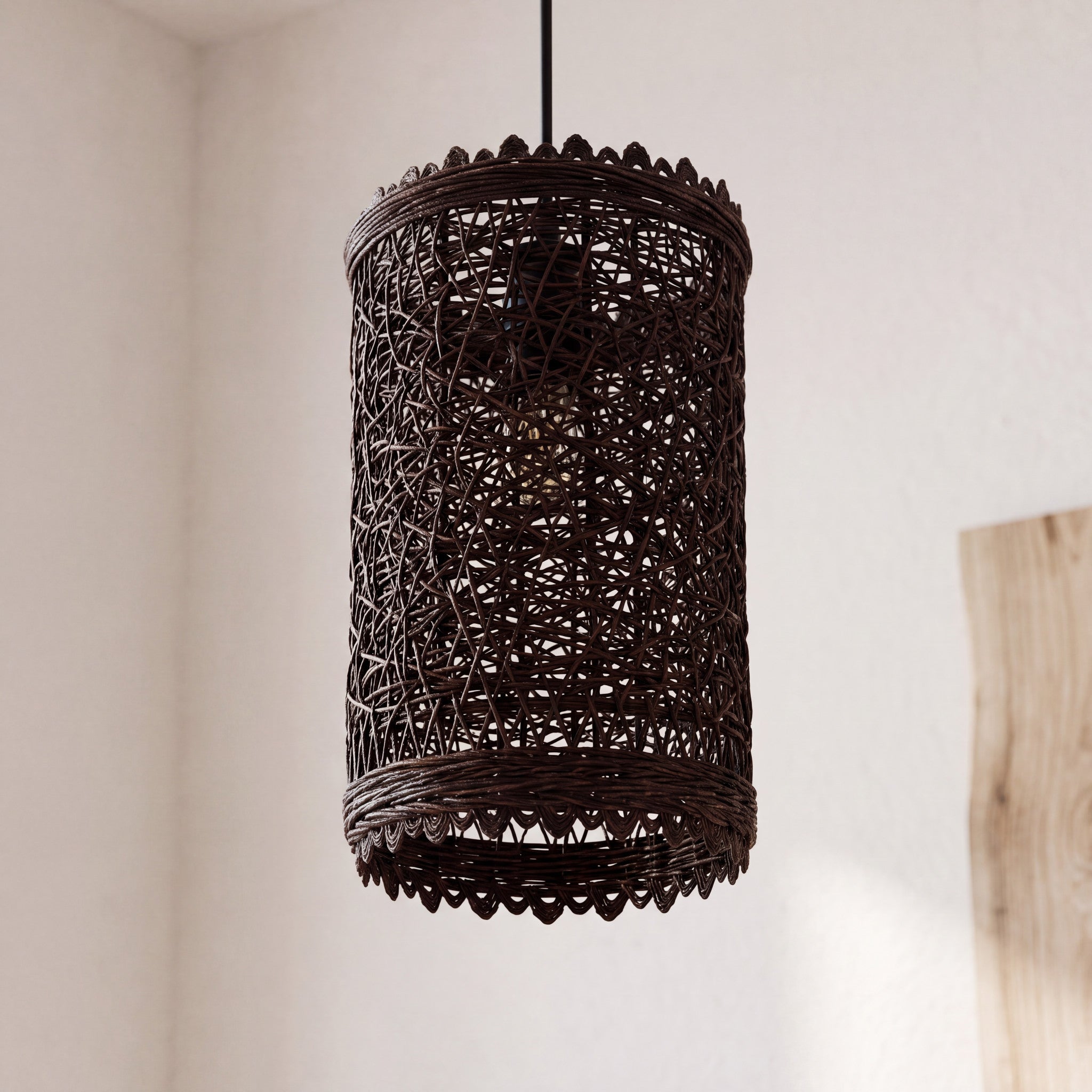 Rattan pendant light with natural woven shade hanging against a neutral wall