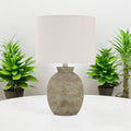 Rustic beige ceramic table lamp styled with green plants
