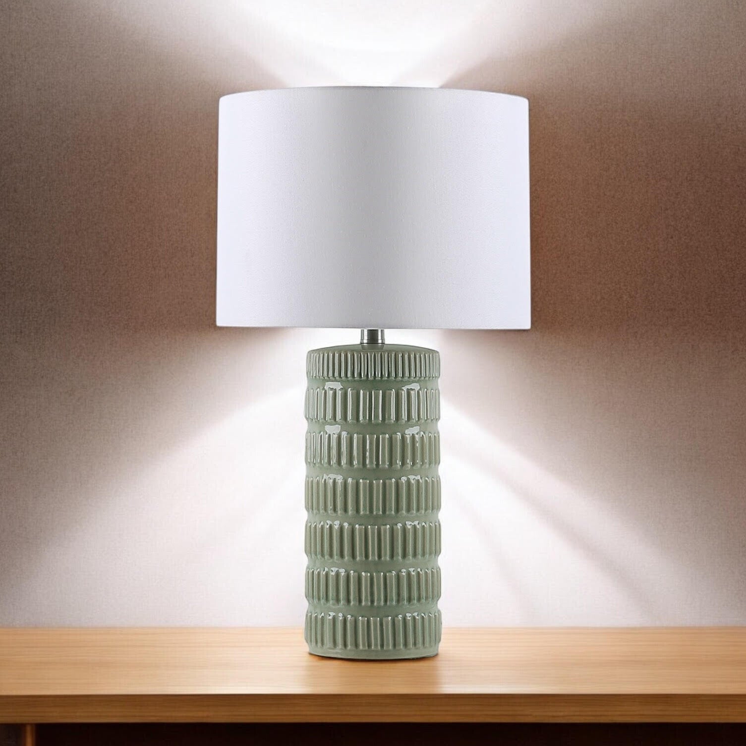 Sage green ceramic table lamp casting a warm evening glow