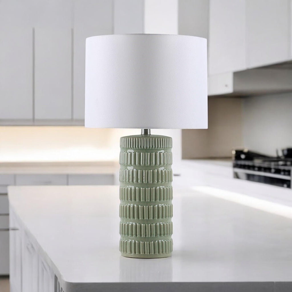 Sage green ceramic table lamp on a bright kitchen island