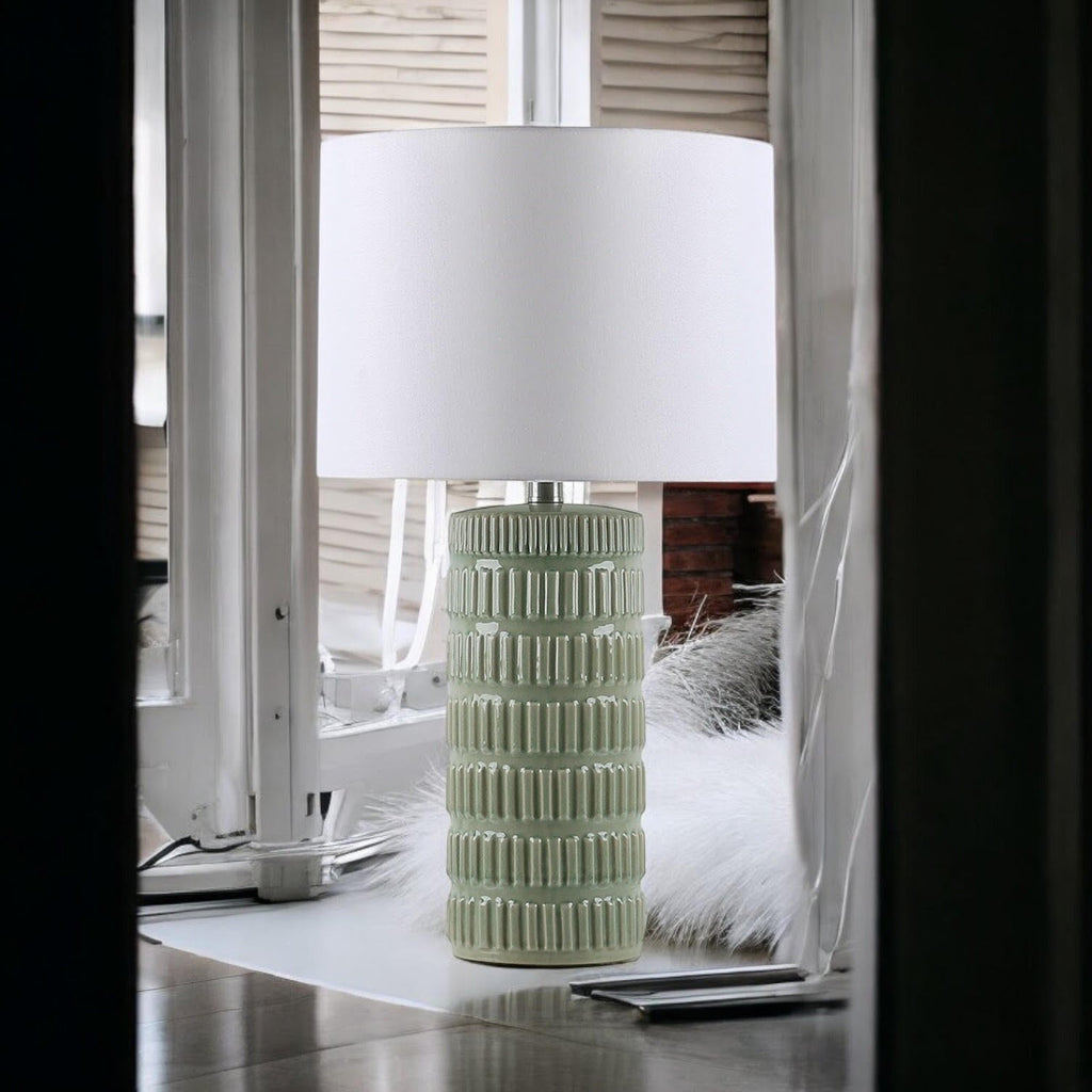 Sage green textured ceramic table lamp beside a window