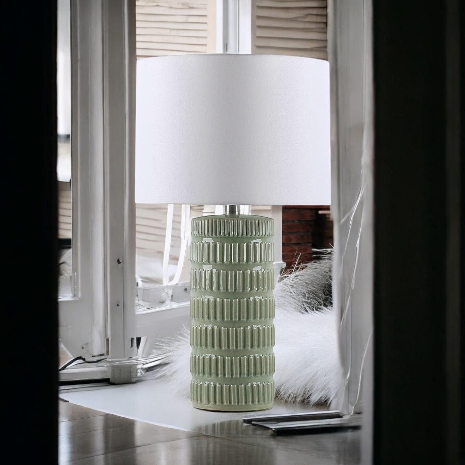 Sage green textured ceramic table lamp beside a window