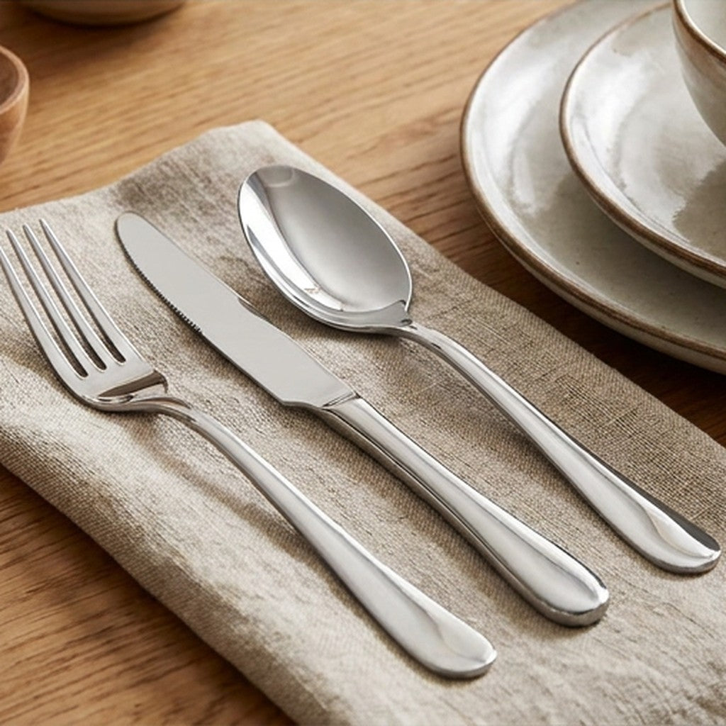 Stainless steel knife fork and spoon beside neutral ceramic tableware