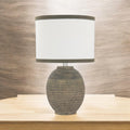 Textured beige ceramic table lamp on a pale wood console