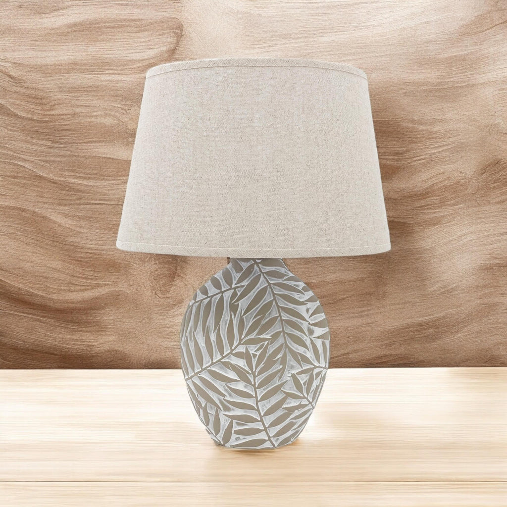 Warm white leaf-relief ceramic table lamp on natural wood
