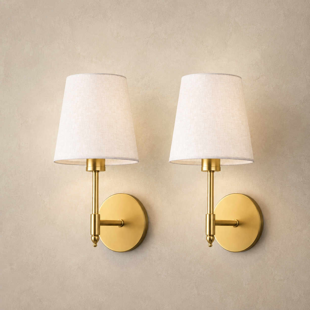 Set of two gold wireless wall lights with white linen shades on a warm neutral wall